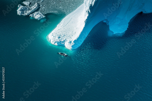 Drone Overview of Humpback whale passing by a iceberg in Greenland, illulisat photo