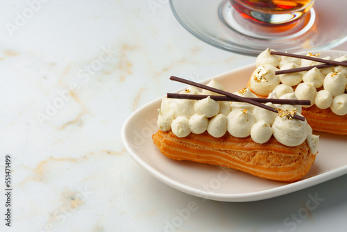 Two eclairs with white custard on whhite plate photo