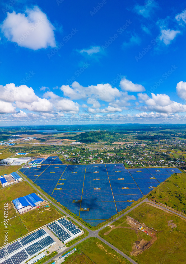 Aerial view of large sustainable electrical power plant with many rows of solar photovoltaic panels for producing clean ecological electric energy in countryside with blue sky