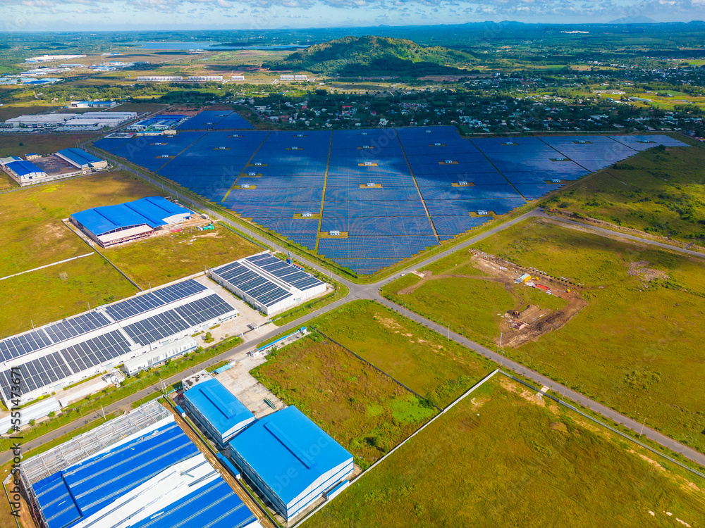 Aerial view of large sustainable electrical power plant with many rows of solar photovoltaic panels for producing clean ecological electric energy in countryside with blue sky