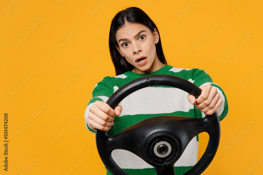 Young confused sad shocked brunette latin woman 30s wear casual cozy green knitted sweater hold steering wheel driving car isolated on plain yellow background studio portrait People lifestyle concept Young confused sad shocked brunette latin woman 30s wear casual cozy green knitted sweater hold steering wheel driving car isolated on plain yellow background studio portrait People lifestyle concept