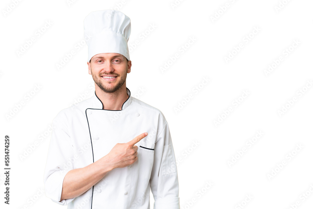 Young caucasian chef over isolated chroma key background pointing to the side to present a product
