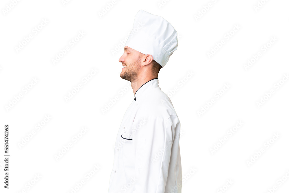 Young caucasian chef over isolated chroma key background laughing in lateral position