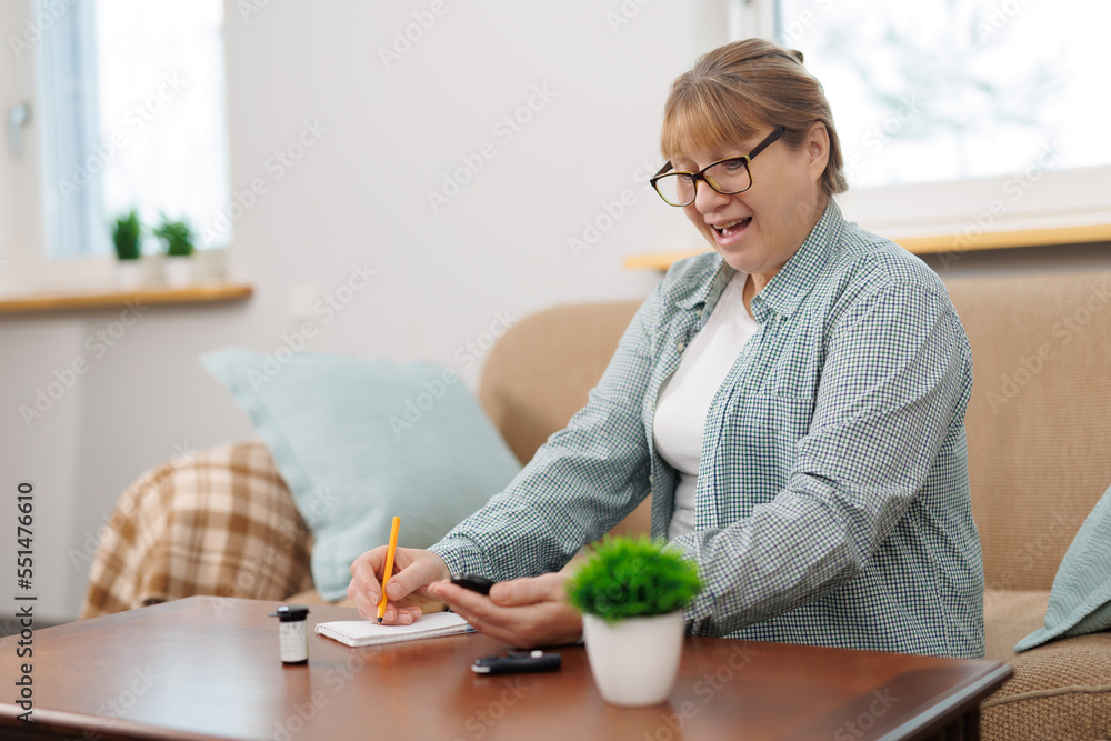Woman measures blood sugar glucose meter, diabetes concept, notebook for writing and monitoring. Woman write blood glucose level from glucose meter, medical consultation and examination in hospital. Woman measures blood sugar glucose meter, diabetes concept, notebook for writing and monitoring. Woman write blood glucose level from glucose meter, medical consultation and examination in hospital.