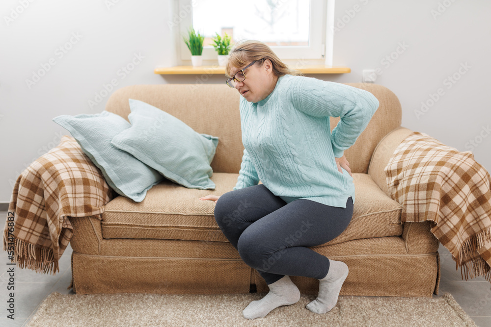 Senior woman suffering from back pain on sofa at home Senior woman suffering from back pain on sofa at home