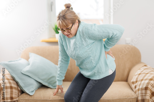 Senior woman suffering from back pain on sofa at home