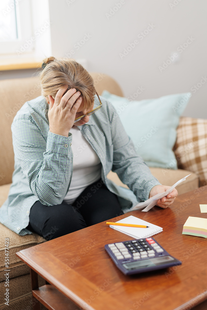 Worried and desperate caucasian woman calculating domestic money expenses doing paperwork and bank bills accounting with calculator suffering stress in financial problem and depression Worried and desperate caucasian woman calculating domestic money expenses doing paperwork and bank bills accounting with calculator suffering stress in financial problem and depression