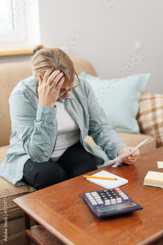 Worried and desperate caucasian woman calculating domestic money expenses doing paperwork and bank bills accounting with calculator suffering stress in financial problem and depression