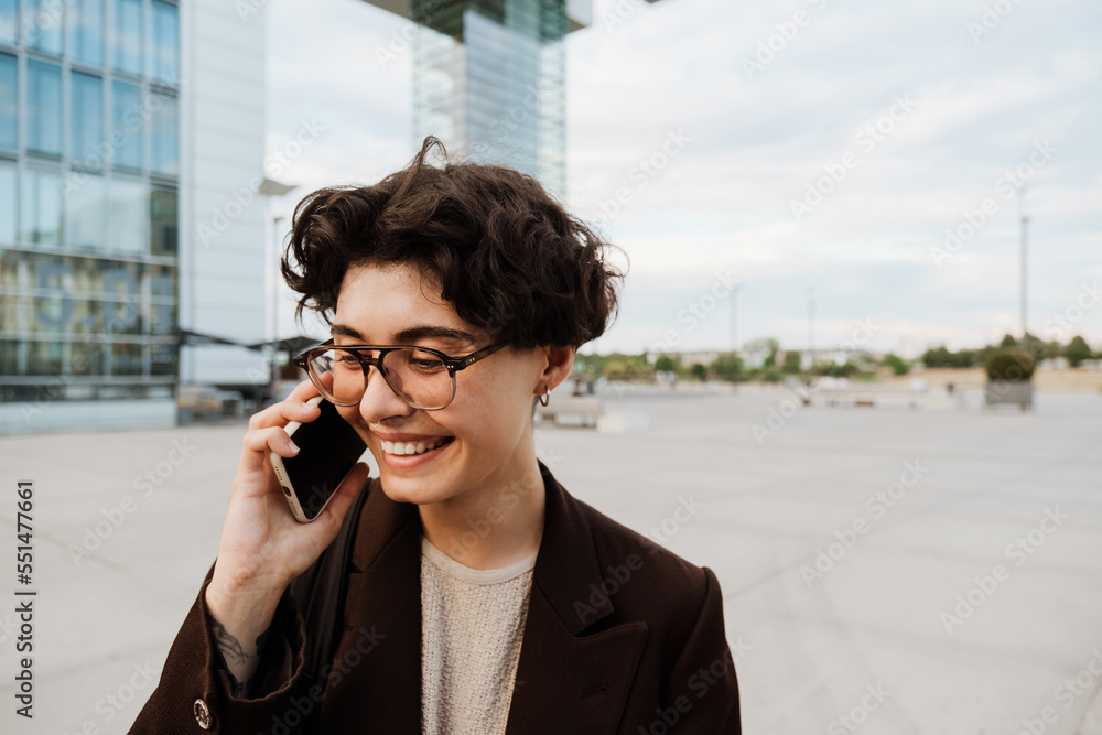 European woman talking on cellphone and laughing at city street European woman talking on cellphone and laughing at city street