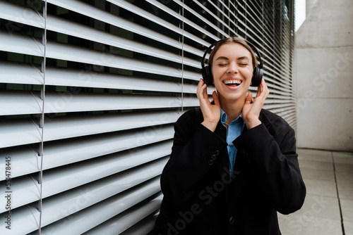 Young woman listening music with headphones while standing outdoors © Drobot Dean