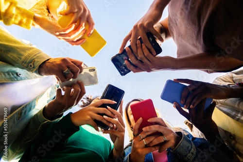 Young group of teenage student people using smart mobile phone outdoors photo