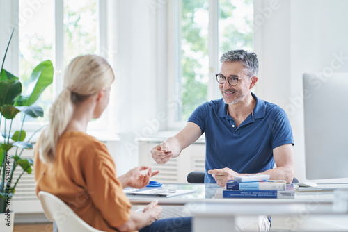 Happy doctor giving medical insurance card to patient in medical practice