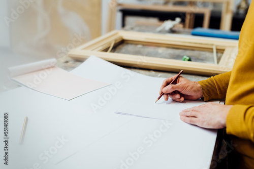 Craftsman drawing at workbench in workshop