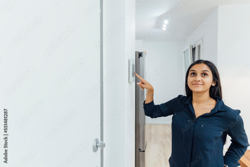Smiling young woman using smart home device on wall Smiling young woman using smart home device on wall