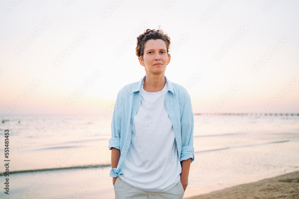 Androgynous woman standing with hands in pockets at beach Androgynous woman standing with hands in pockets at beach