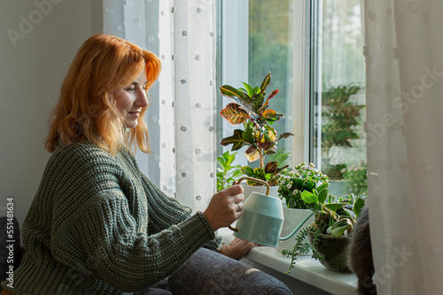 Woman watering house plants at the window