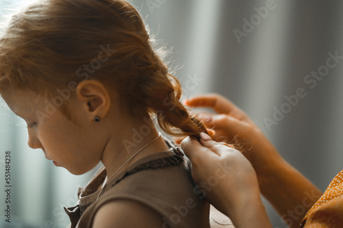 Mother braiding daughter's hair at home photo