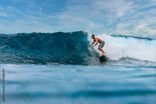 Shirtless male surfer on a wave at sunny day