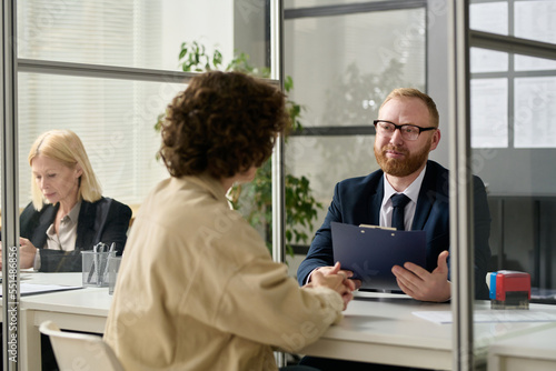 Portrait of smiling male consultant talking to woman in cubicle at agency office