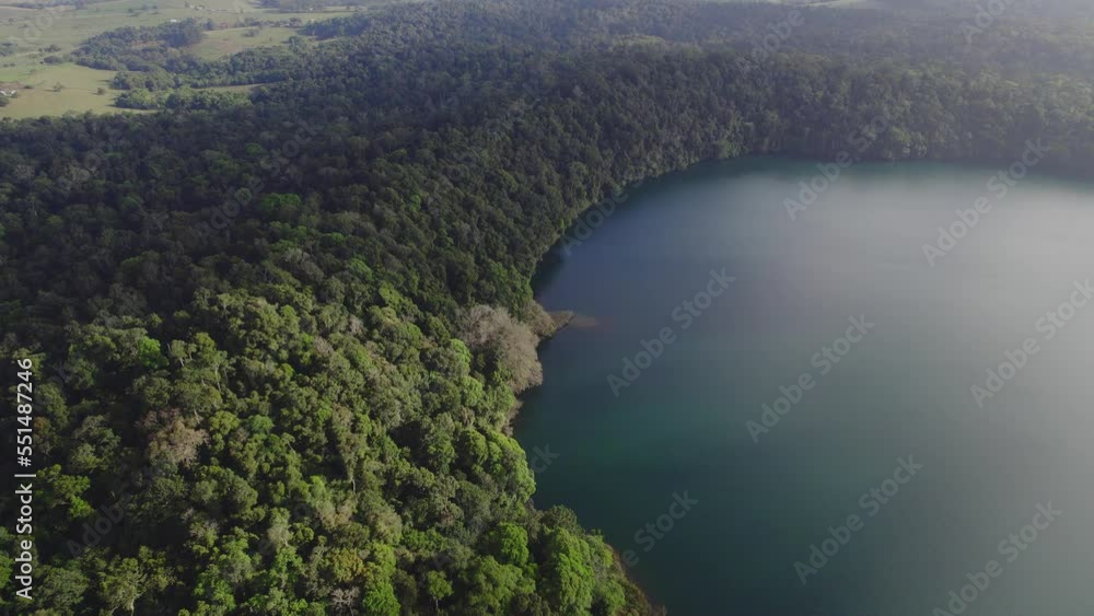 View From Above Of Lake Eacham With Lush Rainforest In Atherton Tableland, Queensland, Australia - drone shot View From Above Of Lake Eacham With Lush Rainforest In Atherton Tableland, Queensland, Australia - drone shot
