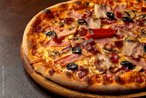 Italian pizza with ham  cheese and olives on a wooden board. Italian cuisine. Close-up