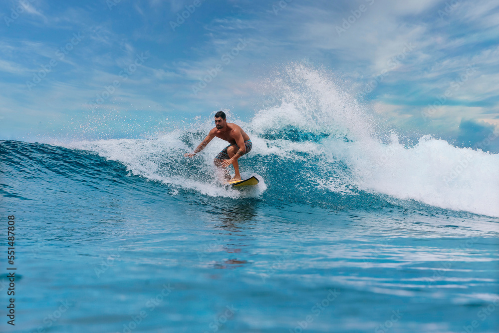 Shirtless male surfer on a wave at sunny day