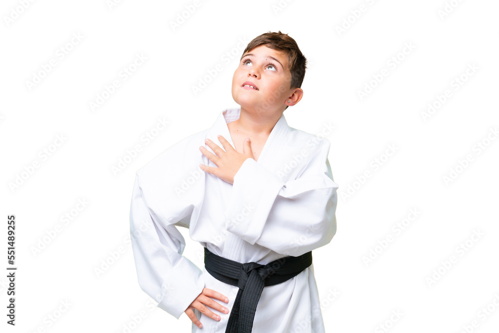 Little caucasian kid doing karate over isolated chroma key background looking up while smiling Little caucasian kid doing karate over isolated chroma key background looking up while smiling
