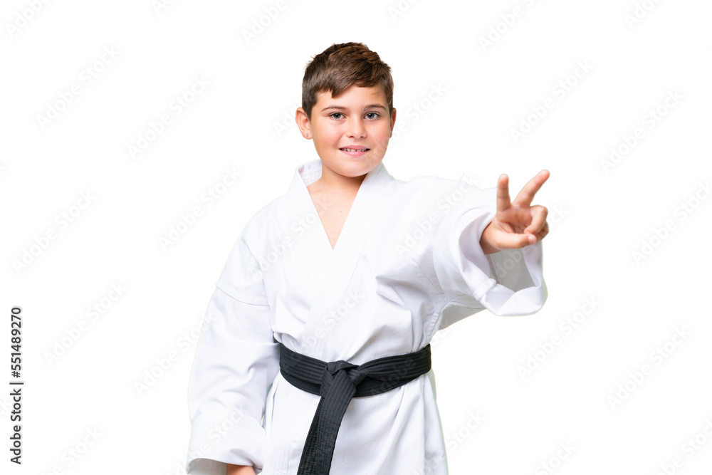 Little caucasian kid doing karate over isolated chroma key background smiling and showing victory sign Little caucasian kid doing karate over isolated chroma key background smiling and showing victory sign