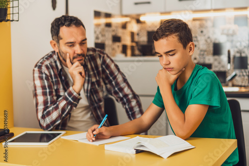 Father is helping his son with learning. They are doing homework together. © djoronimo