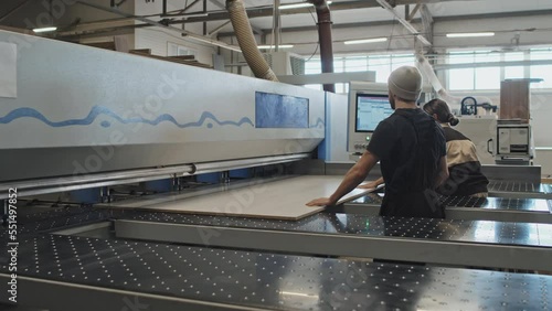 Male and female workers placing wooden board on machine at furniture factory photo