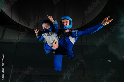 Fototapeta Naklejka Na Ścianę i Meble -  A man teaches a boy to fly in a wind tunnel. Lack of gravity.