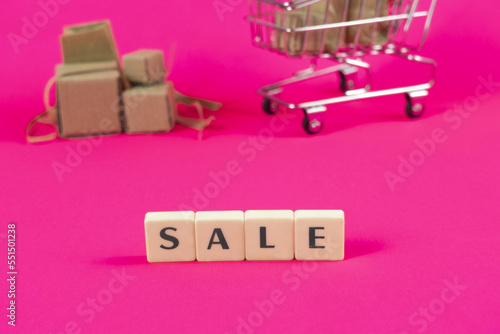 Sale text with cardboard boxes shopping cart in the background, discount and special offer concept, e-commerce banner idea, trolley and letters, buying or selling idea, copy space