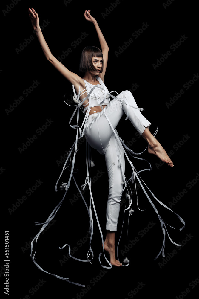 Woman dancing in white pants with flying ribbons and feather