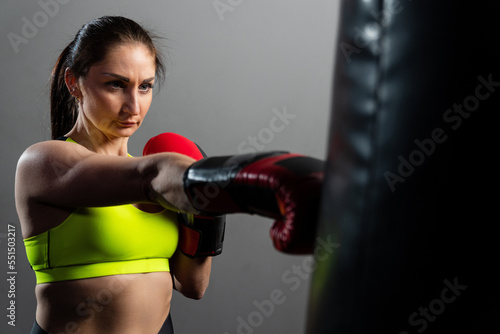 A young woman in red boxing gloves trains in the gym