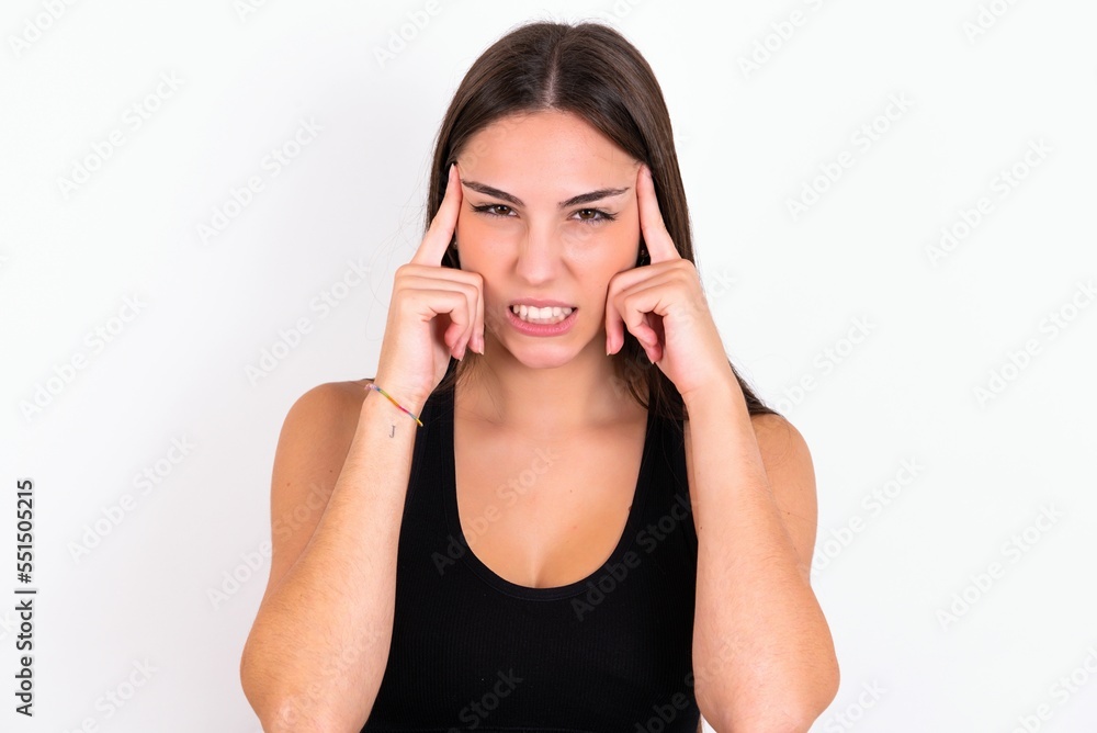 Young caucasian woman wearing sportswear over white background concentrating hard on an idea with a serious look, thinking with both index fingers pointing to forehead. Young caucasian woman wearing sportswear over white background concentrating hard on an idea with a serious look, thinking with both index fingers pointing to forehead.