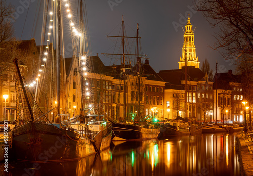 Cityscape of Groningen at night  view of historical ships  canal and tower of the Aa-kerk church