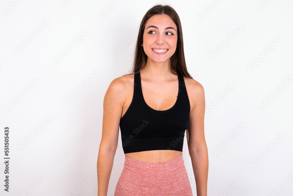 Oops! Portrait of Young caucasian woman wearing sportswear over white background clenches teeth and looks confusedly aside, realizes her bad mistake, Oops! Portrait of Young caucasian woman wearing sportswear over white background clenches teeth and looks confusedly aside, realizes her bad mistake,