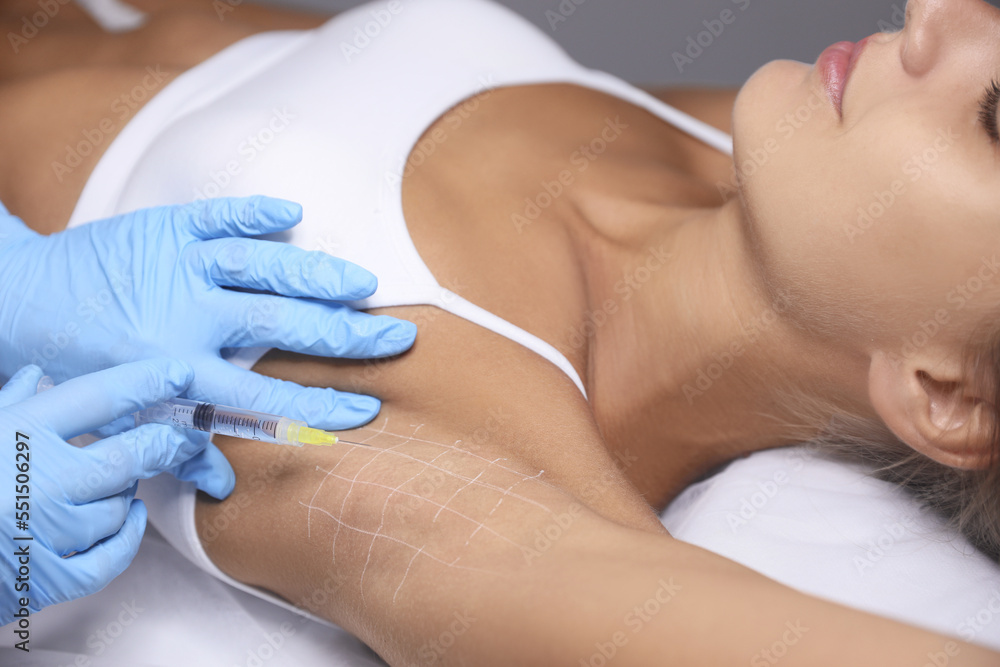 Naklejka premium Young woman getting armpits injection in salon, closeup