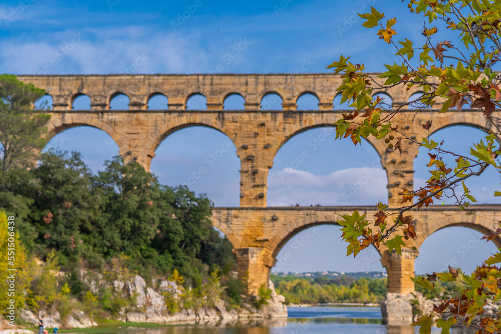 Autumn leaves on branch at Pont du Gard three tier aqueduct, selected focus. Provence