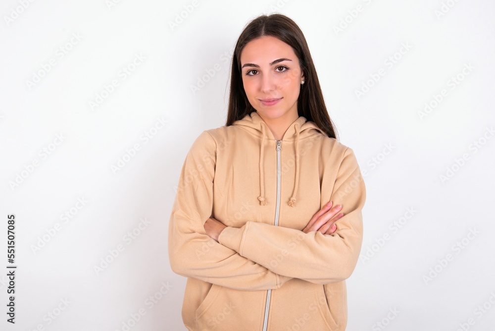 Self confident serious calm Young caucasian woman wearing sweatshirt over white background stands with arms folded. Shows professional vibe stands in assertive pose. Self confident serious calm Young caucasian woman wearing sweatshirt over white background stands with arms folded. Shows professional vibe stands in assertive pose.
