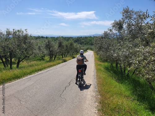 Cycling is awesome: beautiful day with blue sky in tuscany, italy. young sport woman rides her ebike