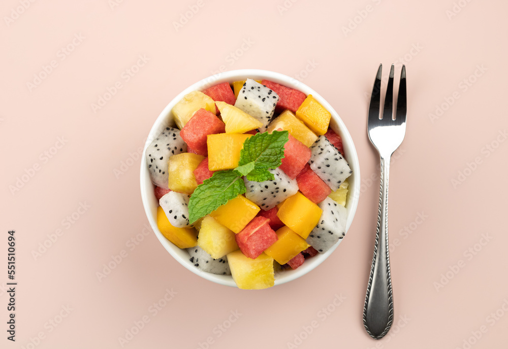 Fruit salad with mango, watermelon, dragon fruit, pineapple, mint on a pink background. Thai tropical fruit salad.