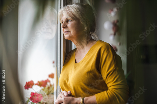 Obraz na plátně Worried elderly woman looking in window