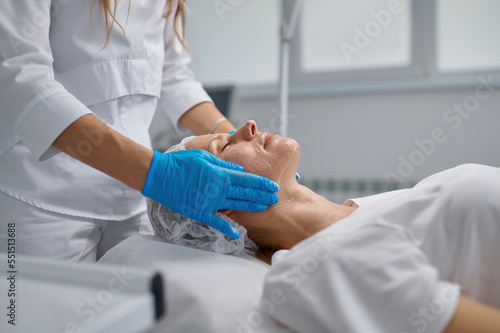 Woman professional doctor beautician applying mask on patient face for skin care