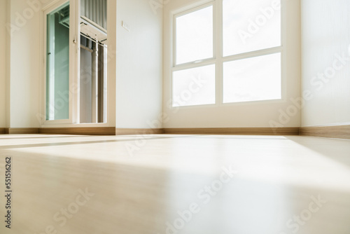Empty room closeup on an engineering wooden floor and baseboard with sunlight from the window. Minimalist interior design and real estate for decoration. Real image with copy space.