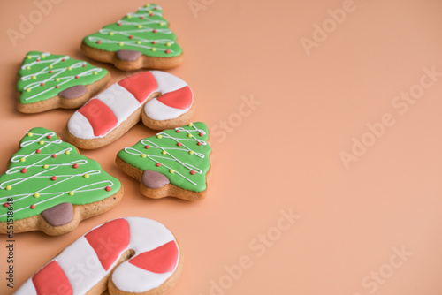 Gingerbread in the shape of a Christmas tree and a cane on peach background with space for text