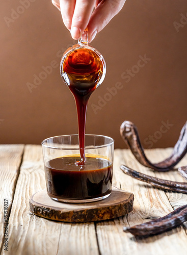 Slika na platnu Healthy carob molasses and woman hand pouring liquid to the cup from glass jar,