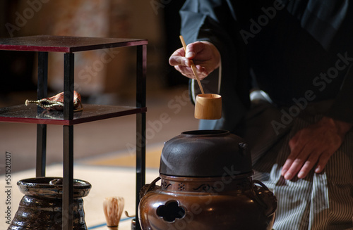 Japanese senior man in traditional kimono, during the tea ceremony. Black background..