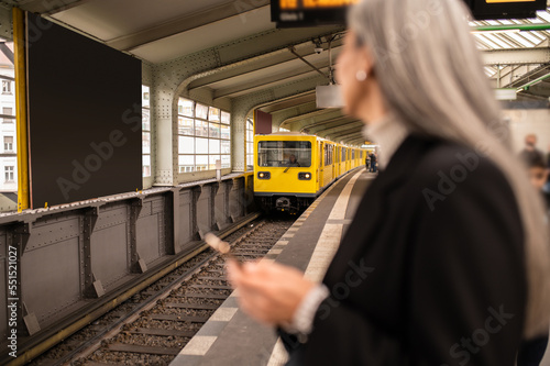 Long-haired woman in a black coat waiting for a train in a subway
