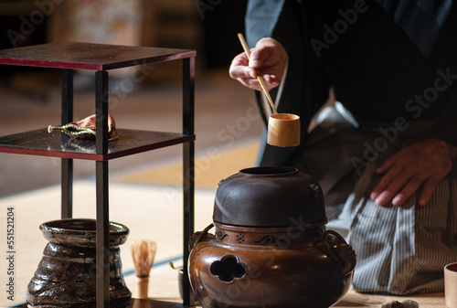 Japanese senior man in traditional kimono, during the tea ceremony. Black background..